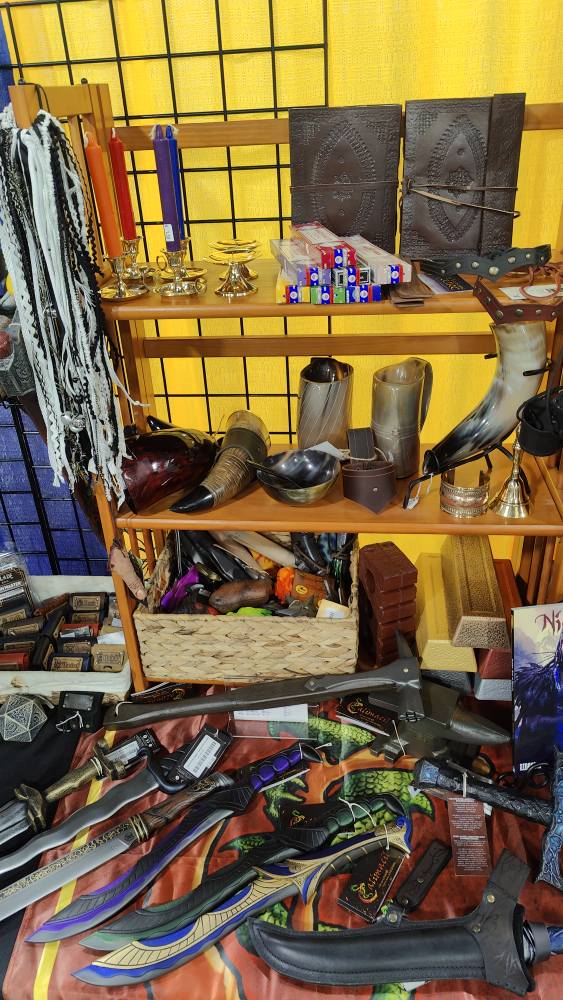 motor city comicon larptopia booth, brass candle holders, spellbooks, incence, drinking horn, horn mug, brass bell, throwing brick, throwing ingots and anvil for blacksmith roleplay larp, blacksmith hammer, calimacil foam daggers, hair tassels